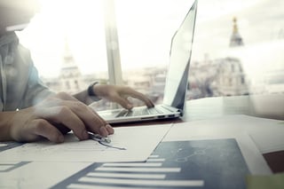 business documents on office table with laptop computer and graph financial diagram and man working in the background.jpeg